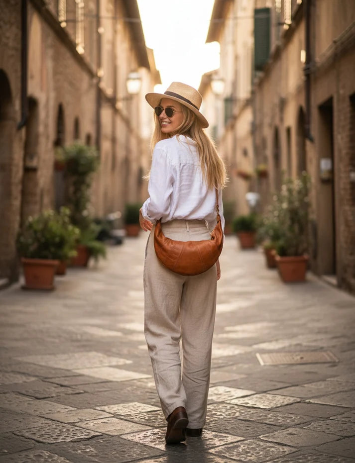 damväska crossbody i halvmåneform av naturligt italienskt läder i en stadsmiljö. Läderväska för axeln som ger karaktär åt vardagsstilen.