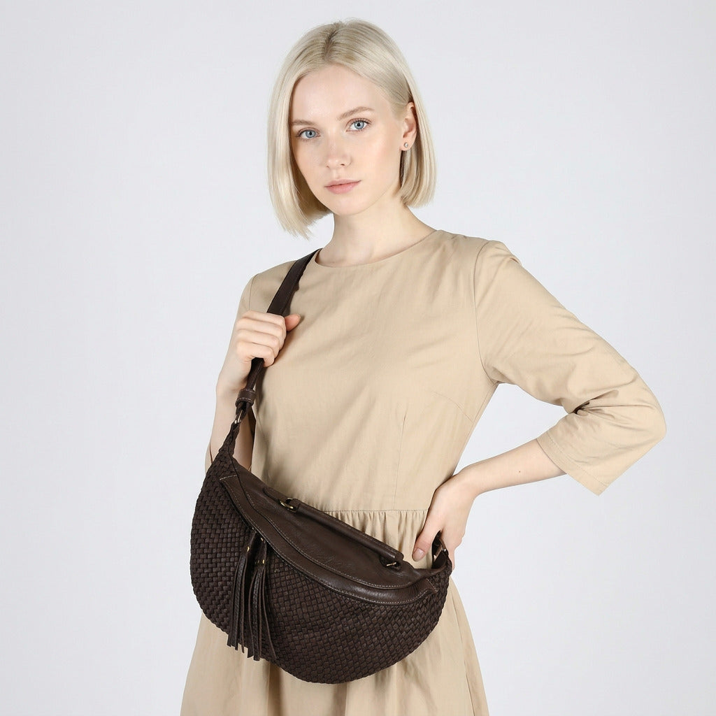 Svart dammidjeväska i läder med flätat mönster, bärs crossbody av modell i studio