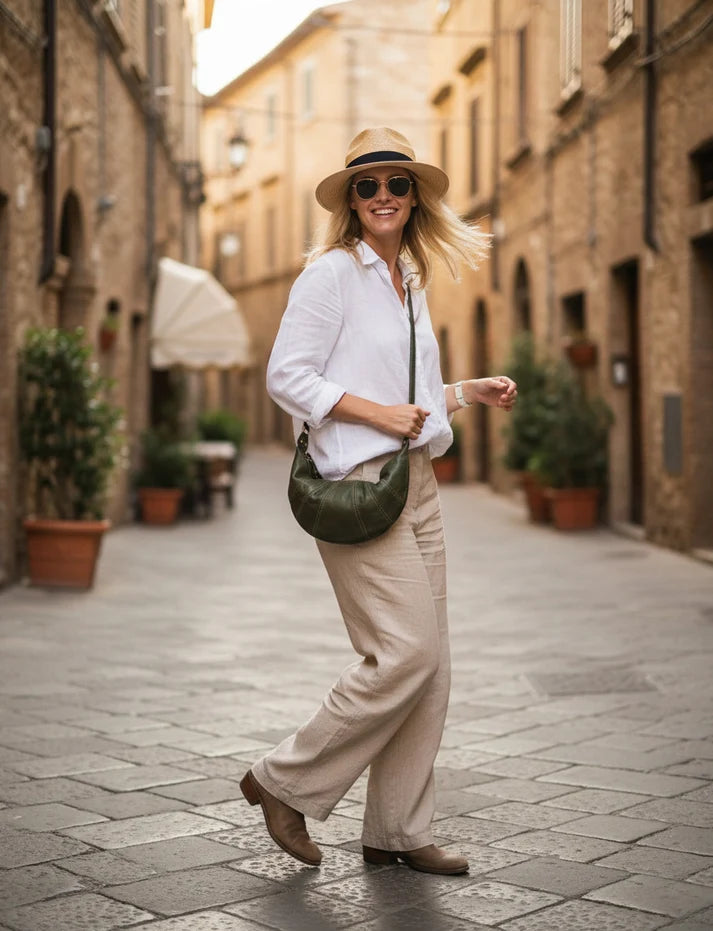 Damväska i halvmåneform av italienskt kalvskinn Lavata i grönt, bärs crossbody under en promenad.