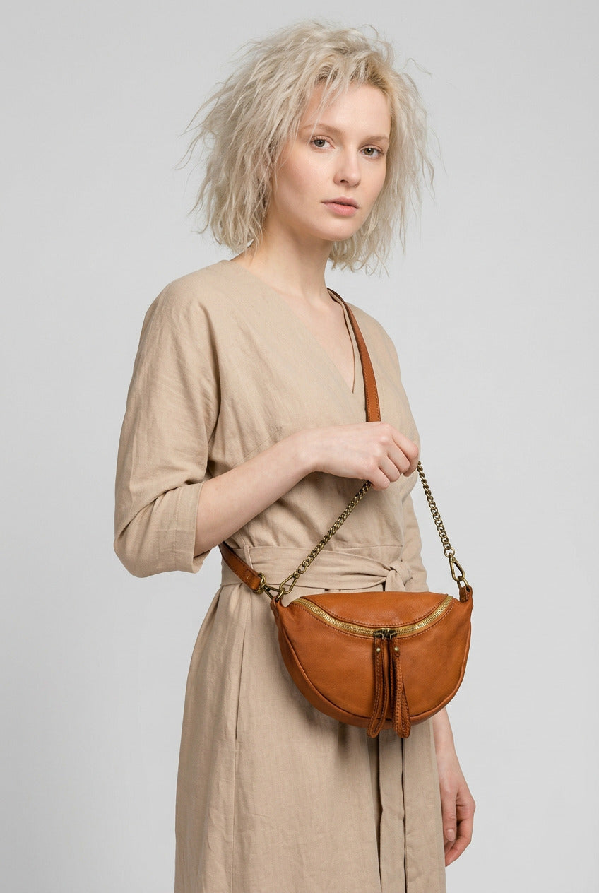 Woman holding a small brown cognac women's shoulder and crossbody bag Amelia made of Italian leather with a gold zipper and tassels