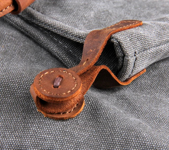 Detail of a leather loop on the flap of a gray canvas bag for women