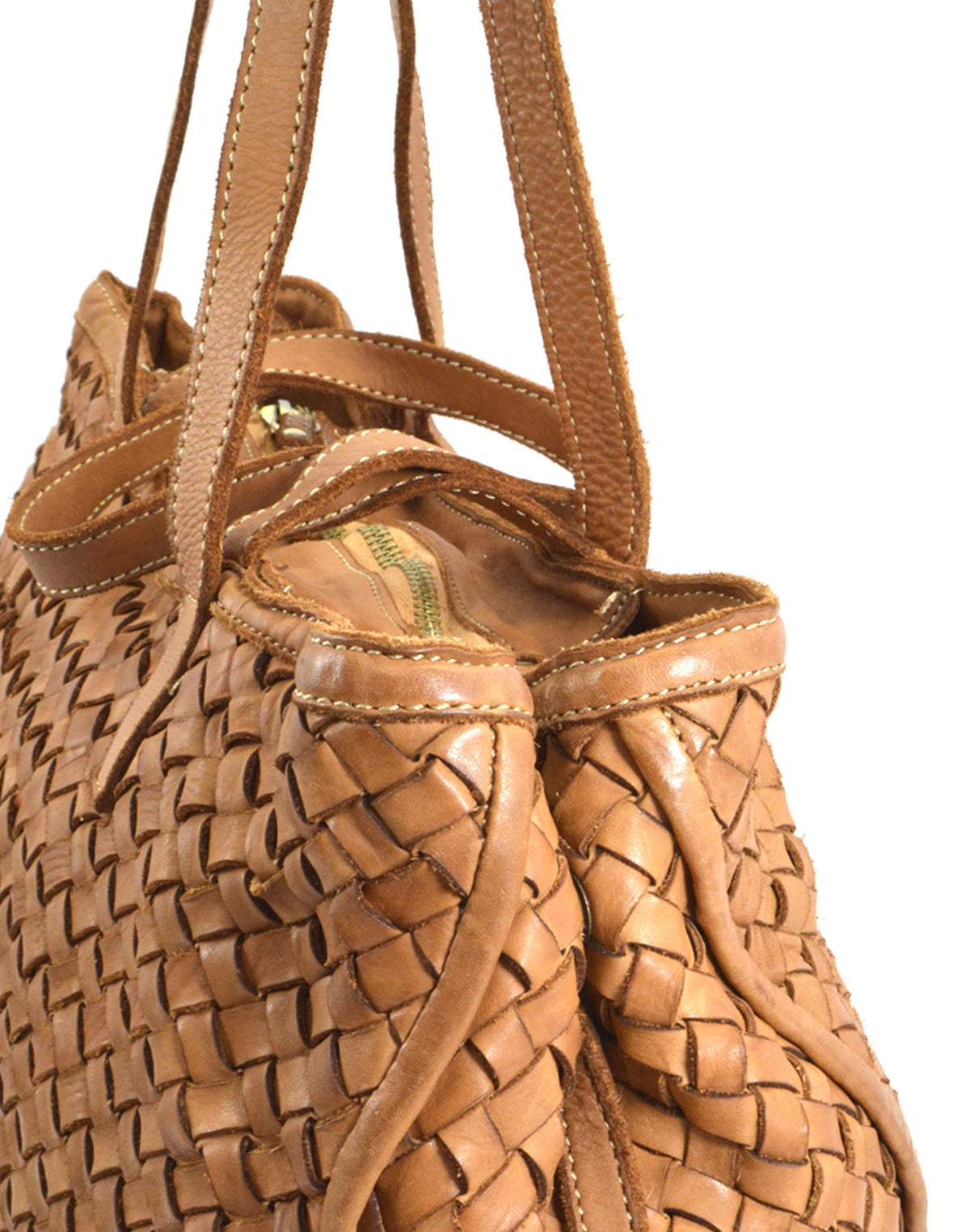 Zbliżenie na plecioną, brązową skórzaną torebkę damską typu shopper z plecioną fakturą, zamykaną na zamek, z uchwytami do ręki i na ramię.